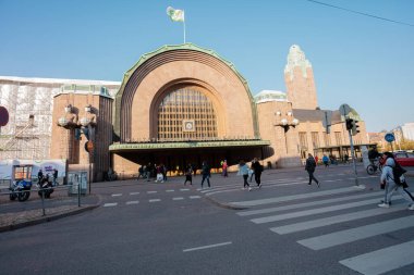 Helsinki, Uusimaa, Finlandiya 2 Ekim 2020 'de tren istasyonunda, ana girişin heykellerini süsleyen tıbbi maskeler takan insanlar. Sonbahar, güneşli bir gün. Coronavirus Enfeksiyon Tehlike Konsepti