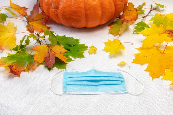 Maple leaves, medical mask, pumpkin on a white background. Concept, autumn, vitamins, protection against coronavirus