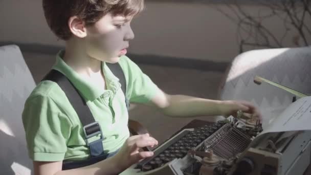 Pleased little six-year-old boy studies the work of an old typewriter. — Stock Video