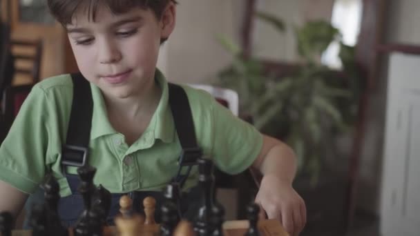 Šest rok starý chlapec uspořádá postavy na šachovnici — Stock video