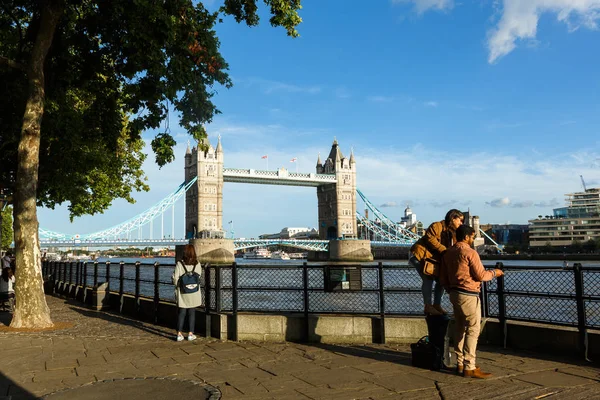 La gente cammina sul terrapieno vicino al Tower Bridge. trasporto fluviale, sera — Foto Stock