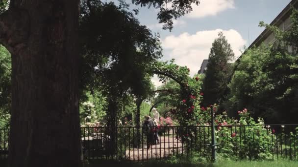 Mensen lopen in het rosarium, botanische tuin in de buurt van broeikasgassen — Stockvideo
