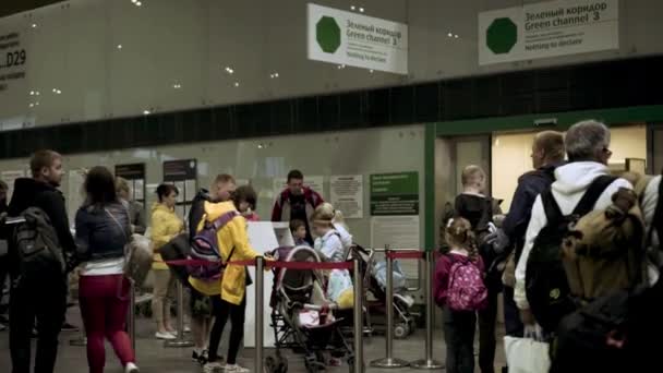 Люди в очереди в зону вылета, зеленый канал, сотрудники аэропорта проверяют документы — стоковое видео