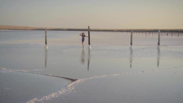 Günbatımı, yürüyüşler Tuz Gölü tuz ahşap sütunlar arasında zevk ince seksi kız — Stok video