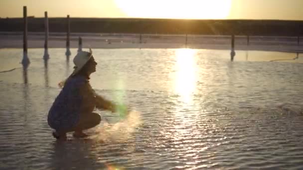 Lyckligt leende flicka njuter av solen, strössel saltvatten sjön i strålar i solnedgång — Stockvideo