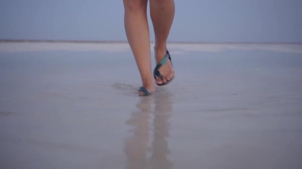 Chica en sandalias verdes salpicar a través de los charcos de lago de sal al atardecer — Vídeos de Stock