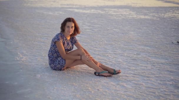 Chica tranquila disfrutando del sol, se sienta en el suelo cubierto de sal cerca del lago — Vídeos de Stock