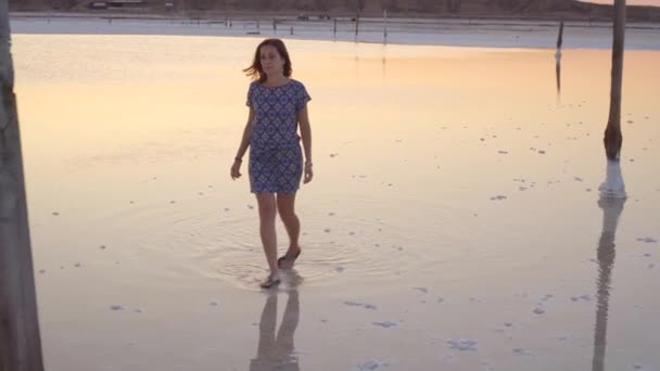 Rustig meisje genieten van zon, wandelen langzaam door het water van een zoutmeer — Stockvideo