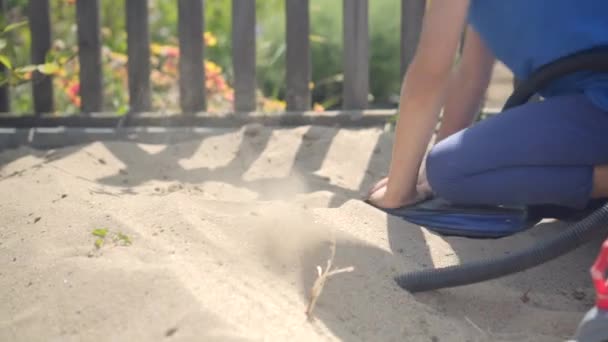 С помощью насоса любопытный ребенок смоделировал извержение вулкана в песочнице — стоковое видео