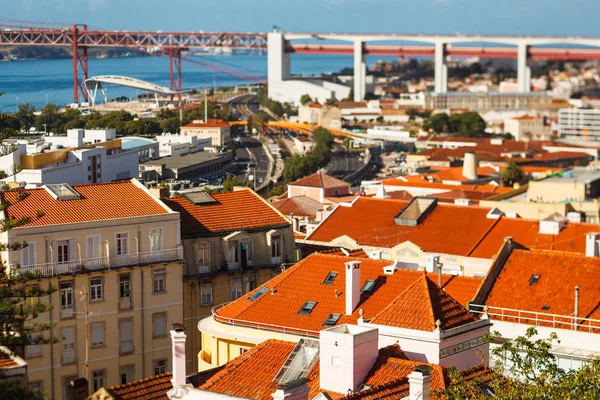 Många ljusa tegeltak i Lissabon, 25: e april bron ansluter till av Almada — Stockfoto