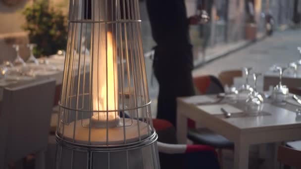 Εξωτερικούς θερμαντήρες αερίου σε σχήμα πυραμίδας σε ένα καφέ. Ο σερβιτόρος ανάβει κεριά — Αρχείο Βίντεο