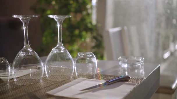 Copos de vinho virados para cima e copos em uma mesa de restaurante no início da noite — Vídeo de Stock