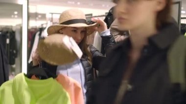 arkadaşlar kışın yaz tatili için hazırlanıyor, bir mağazada şapka deneyin