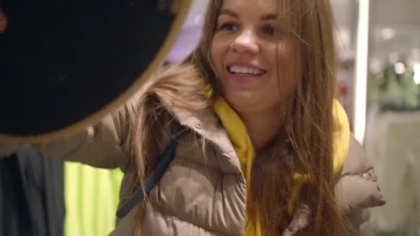 Amigos se están preparando para las vacaciones de verano en el invierno, probarse sombreros en una tienda — Vídeo de stock