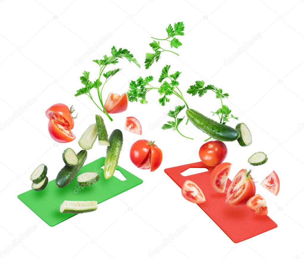 Slices of tomatoes and cucumbers with with parsley leaves fall on the kitchen boards 