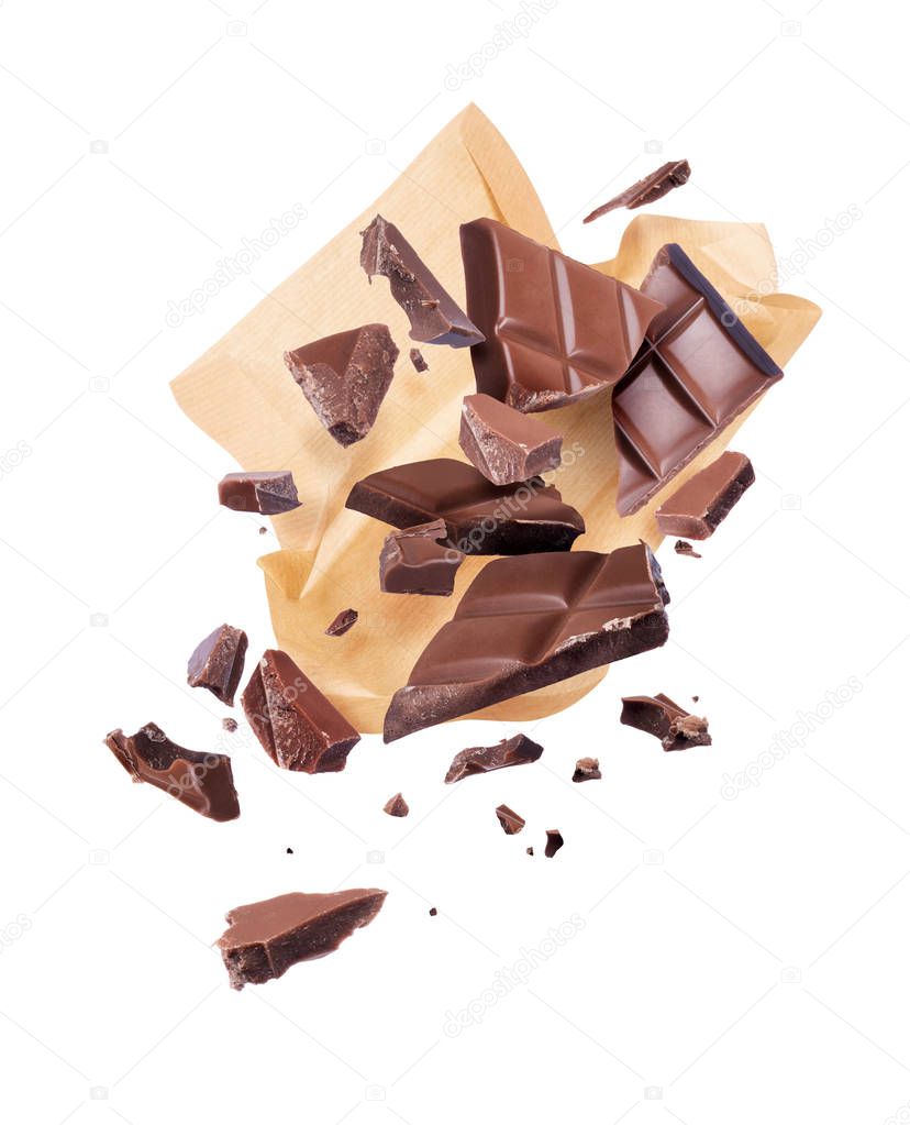 Pieces of crushed chocolate are fly out of a paper wrapper, isolated on white background 