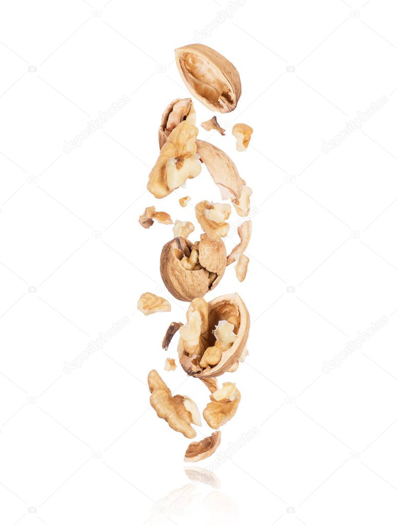 Cracked walnuts fall down isolated on white background