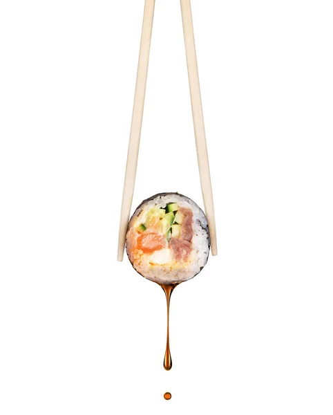 Drop of soy sauce drips from a fresh sushi roll