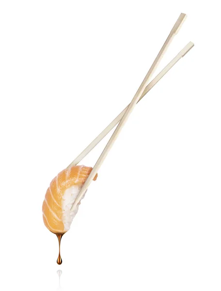 Drop of soy sauce drips from a fresh sushi roll on a white background