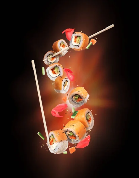 Rolos de sushi frescos com gengibre congelado no ar sobre fundo preto — Fotografia de Stock