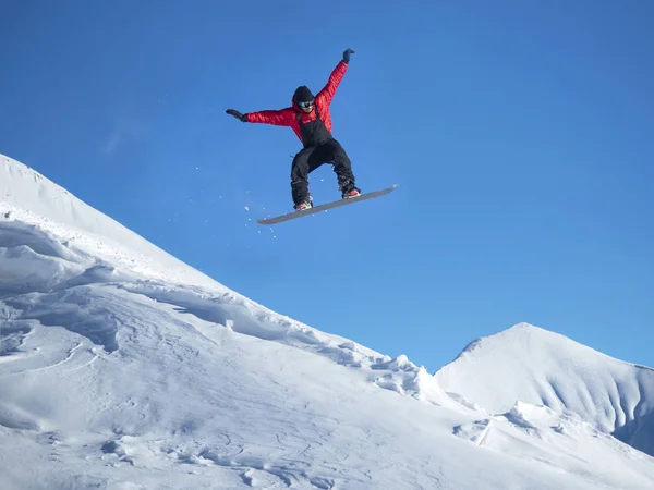 Snowboarder saltar nas montanhas contra o céu azul — Fotografia de Stock