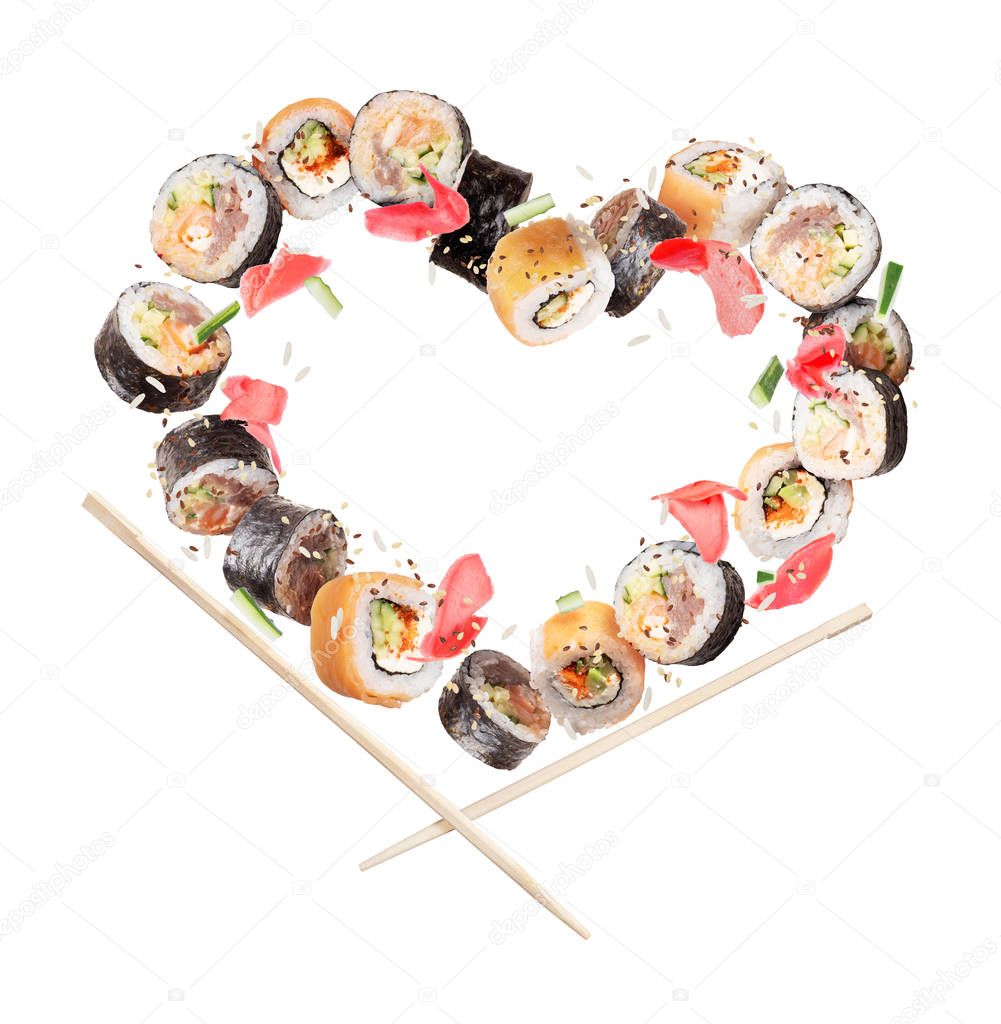 Sushi rolls with chopsticks frozen in the air in the shape of the heart 