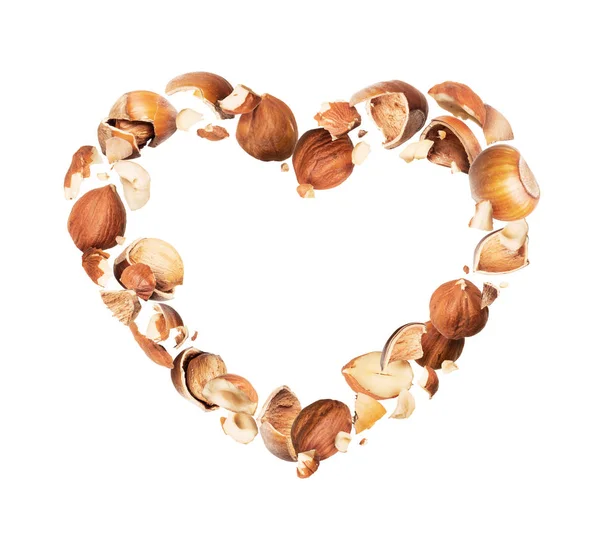 Crushed hazelnuts in the air in the shape of a heart, isolated on a white background Stock Picture