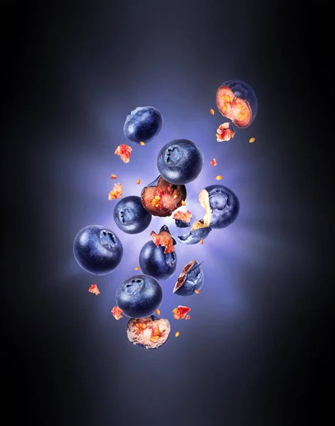 Hela och skivade färska blåbär i luften med blixtens ljus i mörkret — Stockfoto
