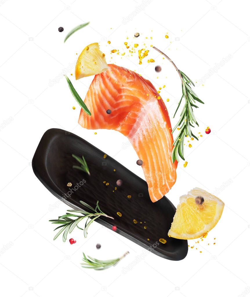 Slice of fresh salmon with spices and lemon in the air , isolated on a white background