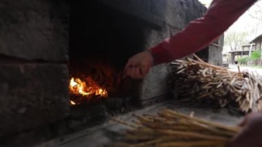 Bir adam fırın yangın kindles. Ağır çekim.