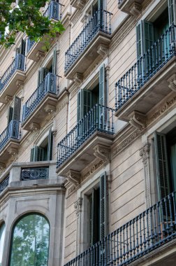 A tenement house made of light brick with blue balconies and a bay window.