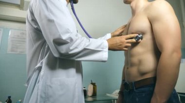 Göğüs Hastanesi ofisinde atletik bir adam kontrol doktor. Doktor muayene genç erkek hasta stetoskop ile. Tıbbi işçi dinleme kalp atışı bir adam. Yakın çekim