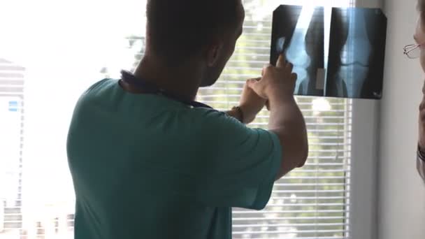 Medische medewerkers in het ziekenhuis kijken en analiseren röntgenfoto 's. Medisch consult met elkaar. Twee mannelijke dokters bekijken MRI foto en praten erover. Close-up Achteraanzicht — Stockvideo