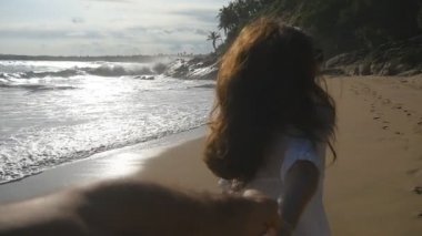 Genç kadın çekin sevgilisi deniz kıyısında vurdu beni takip edin. Erkek elini tutarak ve tropikal egzotik kumsalda okyanusa çalışan kız. Yaz tatili ya da tatil. Bir bakış açısı. POV ağır çekim
