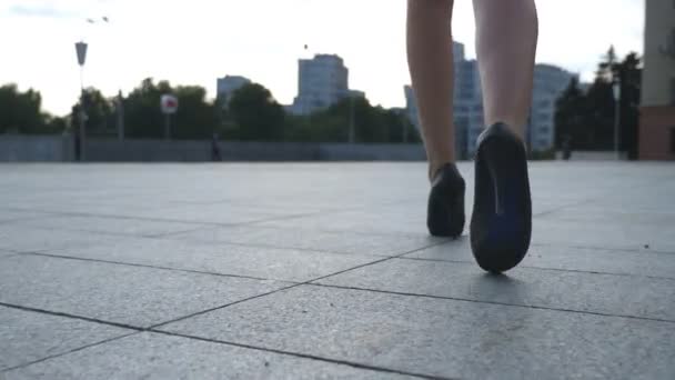 Siga a las piernas femeninas en zapatos de tacón alto caminando por la calle urbana. Pies de mujer de negocios joven en calzado de tacón alto que va en la ciudad. Chica entrando al trabajo. Cámara lenta Primer plano Vista trasera trasera — Vídeo de stock