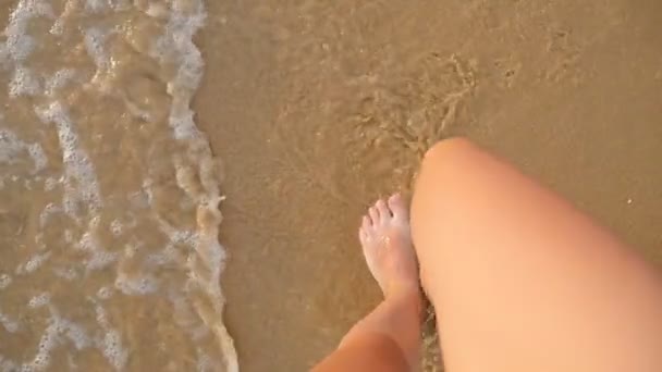 海でビーチの黄金の砂でステップの若い女性の視点海の近くを歩く女性の脚。波と砂浜に行く女の子の素足。夏休みや休日スローモーションのクローズ アップ — ストック動画
