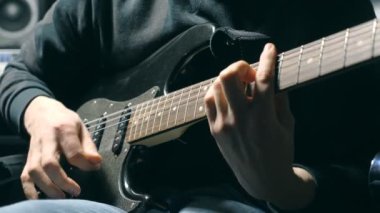 Dizeleri, gitarist parmakları kapatın. Mens çalış solo rock müzik silah. Eller erkek müzisyen elektro gitar çalmak. Stüdyoda güzel siyah arka plan. Ağır çekim yakın çekim