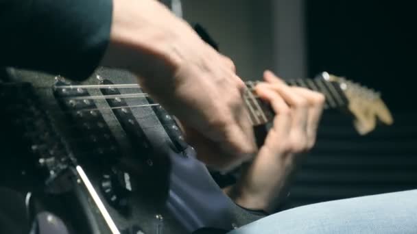 文字列でギタリストの指を閉じます。メンズは腕ロック ・ ミュージックの再生ソロです。男性ミュージシャンのエレク トリック ギターで演奏の手。スタジオでの美しい黒の背景。スローモーションをクローズ アップ — ストック動画