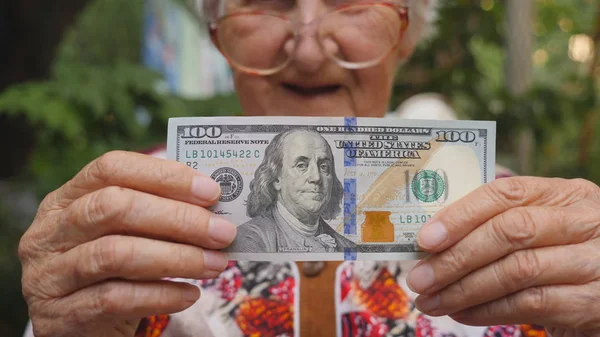 Gözlük kamera ve gülümseyen yüz doları tasarısının açık gösterilen yaşlı kadın. Büyükanne holding nakit dışında. Para kavramı. Yavaş hareket kapatmak