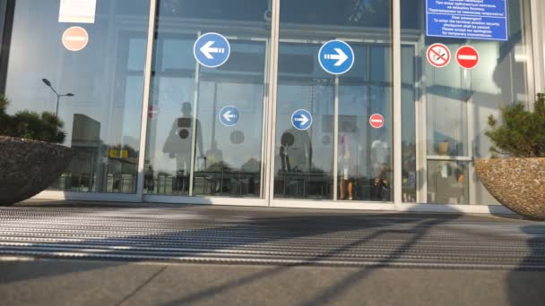 Twee zakenlieden gaan naar het vliegveld met zijn bagage. Jonge mannen lopen door automatische deursluiters voor moderne terminal. Reis bedrijfsconcept. Slow motion — Stockvideo