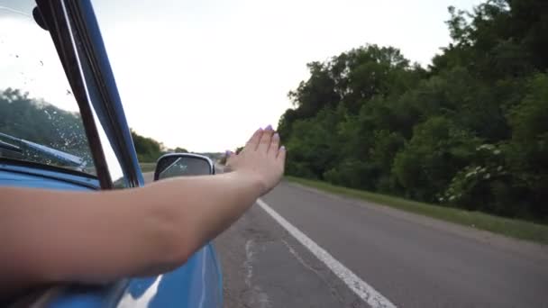 Vrouwelijke arm buiten retro auto spelen met wind tijdens zomer reis. Jonge vrouw zwaaiend met haar hand in wind op reis. Meisje legt haar arm uit het raam van de oude auto te voelen van de wind. Slow motion — Stockvideo