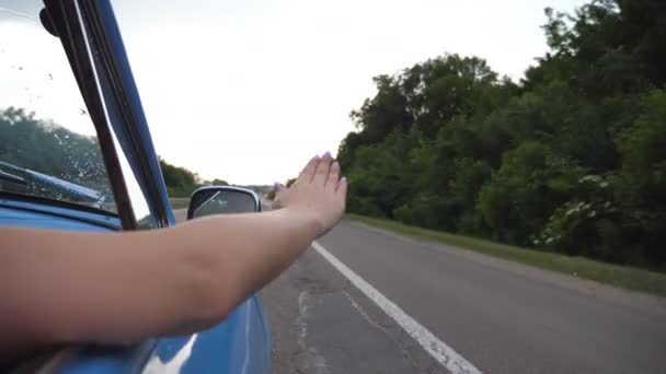 Brazo femenino fuera del coche retro jugando con el viento durante el viaje de verano. Mujer joven saludando con su mano en el viento en el viaje. Chica pone su brazo por la ventana del coche viejo para sentir la brisa. Movimiento lento — Vídeos de Stock