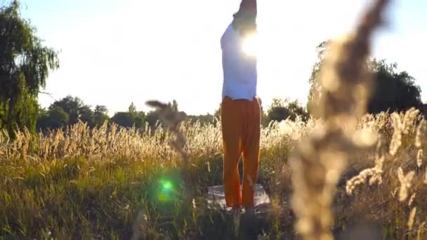 Молодой Человек Практикует Йогу Коврике Вид Через Травяное Поле Солнечный — стоковое видео