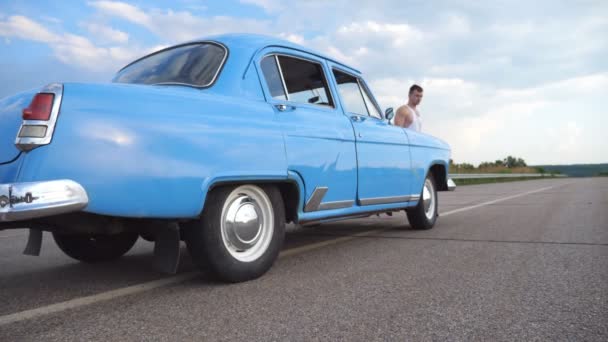 Chica está saliendo de retro auto y huyendo con su novio. El joven abre la puerta del coche viejo para su novia. Mujer saliendo de un automóvil de época. Ocio de pareja feliz. Moción lenta — Vídeo de stock