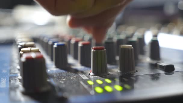 Mãos masculinas de engenheiro de som ajustando os botões na mesa do misturador. Editor de áudio trabalhando em um estúdio de gravação moderno. Vista lateral Fechar em câmera lenta — Vídeo de Stock