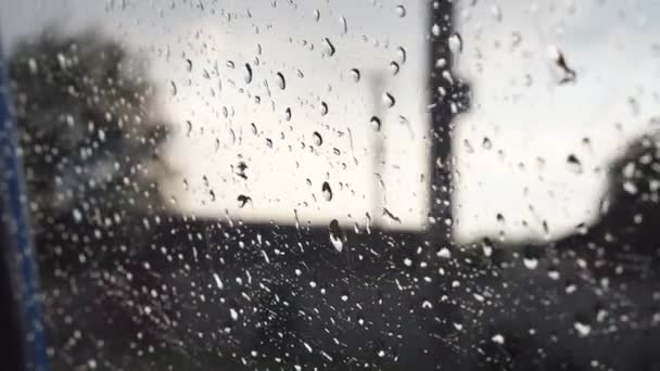 Close up de gotas de chuva na janela do carro durante o mau tempo com fundo borrão. Gotas de água caem sobre o vidro do automóvel durante a condução no campo. POV Movimento lento — Vídeo de Stock