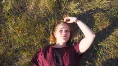 Üstten görünüm çayır, yeşil çim üzerinde yalan ve rüya sarı saçlı güzel kız. Genç kadına rahatlatıcı alanı ve doğanın tadını çıkarın. Güneş ışınlarının kadın yüzünde Parlatıcı. Yakın çekim