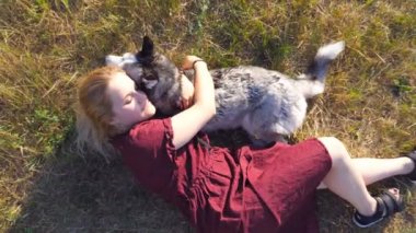Çayır çim üzerinde yalan ve onu husky köpek sarılma sarı saçlı güzel kadın. Genç kız onu evde beslenen hayvan vasıl alan birlikte vakit. Sevgi ve dostluk ile Evcil hayvan. Üstten görünüm