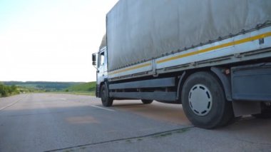 Kamera bir otoyolda sürüş kamyon için izleyin. Arka plan, güzel manzara ile kırsal yoluyla kamyon sürmek. Asfalt, kamyon sürüş tekerlek. Yan görünümü ağır çekim yakın çekim