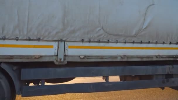 Vrachtwagen rijdt door het landschap met prachtige landschap op de achtergrond. Wielen van truck rijden op asfalt. Vrachtwagen rijden op een snelweg. Zijaanzicht close-up in Slow motion — Stockvideo